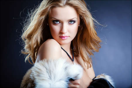 Sensual sexy girl blonde in a fur coat on a blue background, close upの写真素材