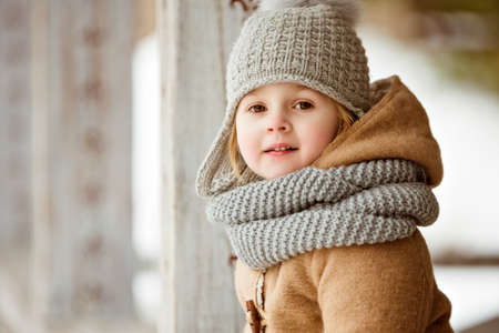 portrait of a very cute beautiful girl child in a beige coat and a gray hat, close upの写真素材