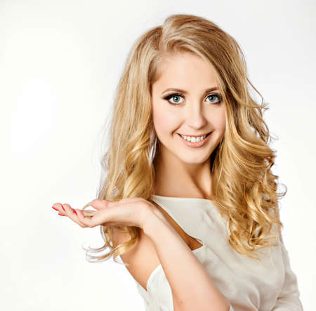 An attractive portrait of a cute smiling girl blonde with clean and well-groomed skin delicate makeup in a white dress on a white background in Studio, close-upの写真素材