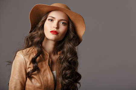 Sexy beautiful girl with shiny hair and a hat with red lips, close-up portrait. Studioの写真素材