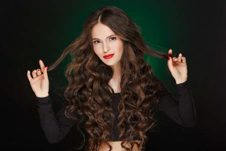 Very beautiful glamor girl with plush healthy curly hair in the studio, close-up, portraitの写真素材