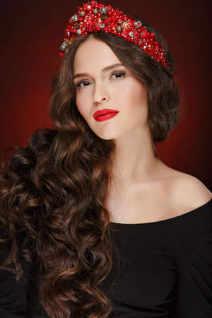 Very beautiful glamorous girl with red tiara and chic healthy hair in studio, close-up, portraitの写真素材