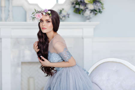 Portrait of a beautiful sexy brunette girl with brown eyes in a delicate dress and a wreath of flowers on her headの写真素材