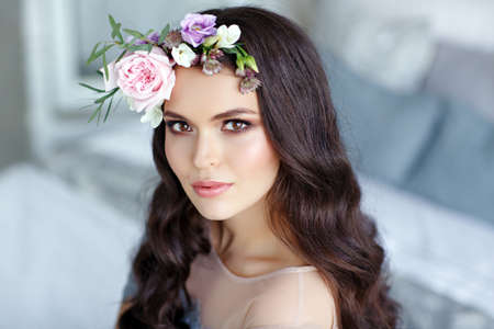 Portrait of a beautiful sexy brunette girl with brown eyes in a delicate dress and a wreath of flowers on her headの写真素材
