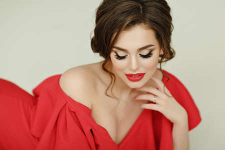 Elegant sexy brunette girl in a red dress looking down