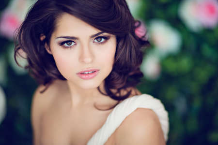 Very beautiful girl brunette in a beige dress looks straight, close up