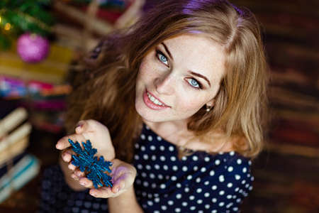 Beautiful red-haired girl with blue eyes holding a snowflakeの写真素材