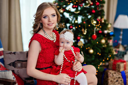Mother and daughter in red on the background of the Christmas treeの写真素材