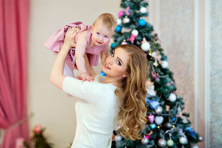 happy mother and daughter in bright clothing on the background of the Christmas treeの写真素材