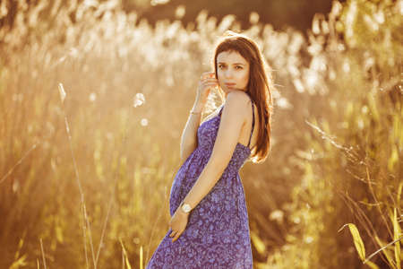 Beautiful tender pregnant woman smiles and enjoys a sunny summerの写真素材