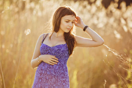 Beautiful tender pregnant woman smiles and enjoys a sunny summerの写真素材