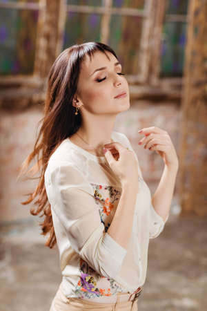 Portrait of a sensual beautiful brunette with eyes closed in the interiors of the house in beigeの写真素材