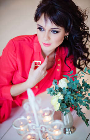Portrait of a very beautiful sexy girl in a red dress on the floor surrounded by eucalyptusの写真素材