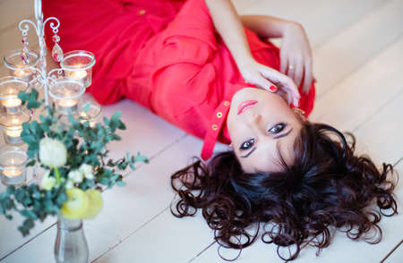 Portrait of a very beautiful girl in a red dress on the floorの写真素材