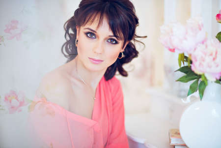Portrait of a beautiful girl brunette in the background pion flowersの写真素材