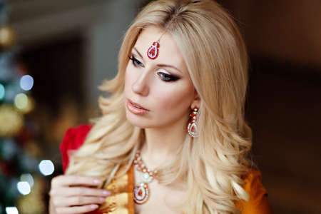 beautiful blonde girl in Indian red saree around the Christmas tree, close upの写真素材