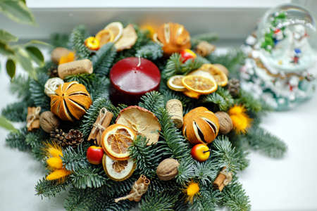 Christmas wreath of Christmas trees, tangerines, oranges and berries with red candleの写真素材