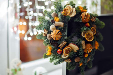 Christmas wreath of Christmas trees, tangerines, oranges and berries on a background of Christmas lightsの写真素材