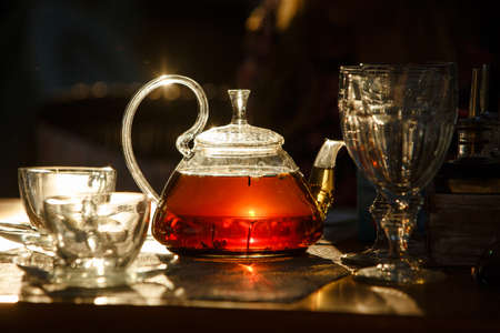 Transparent glass teapot with black tea glows in the sun the last raysの写真素材