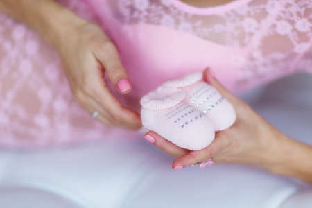 Pregnant woman's belly with pink baby booties