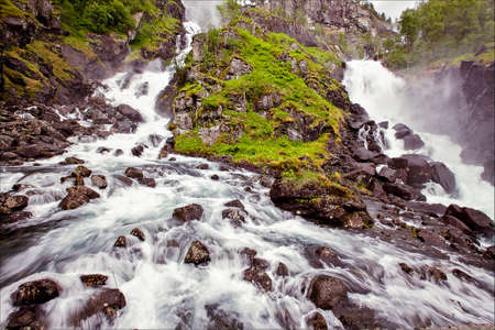 very beautiful waterfall in Norway with fast-flowing water, big rocks with lichen summerの写真素材
