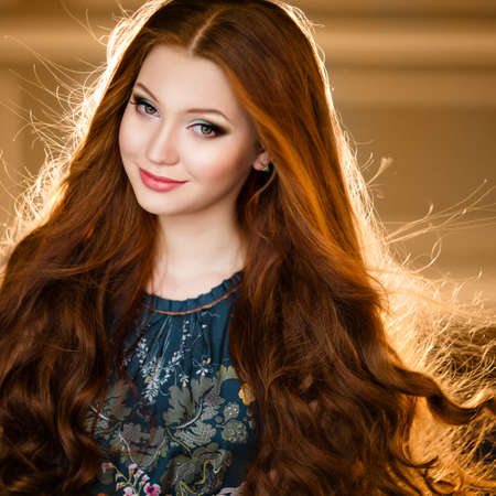 Portrait of a beautiful girl with red hair in a green dress backlitの写真素材