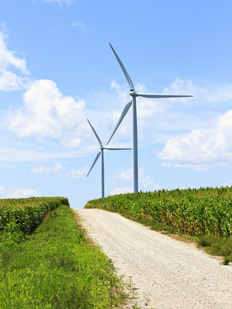 Wind turbines provide energy in a rural area on a dirt roadの写真素材
