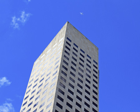 The top of a towering skyscraper in front of blue skyの写真素材