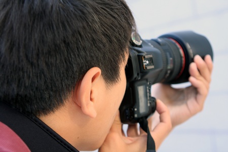 young man photographer doing photos by digital camera の写真素材