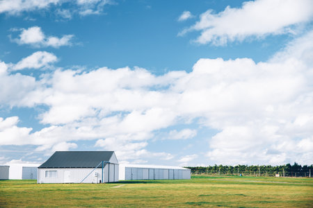 Steel barn on a farm with cloudy blue sky.の写真素材