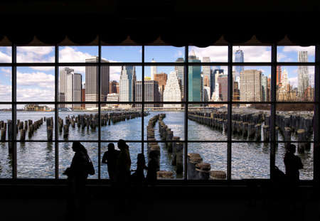 Manhattan from Brooklyn Bridge Park viewed through a window with people silhouetted in the firegroundの写真素材
