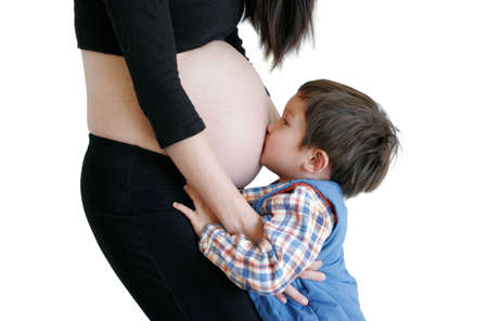 Three years hold kissing mom's belly isolated on pure white backgroundの写真素材