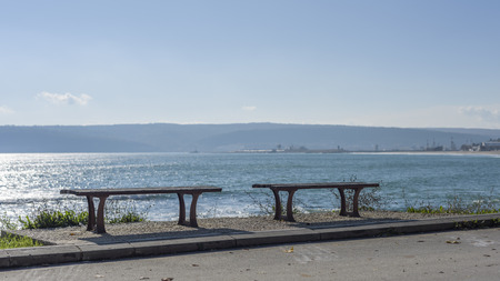 Two benches in front of the sea in a sunny dayの写真素材