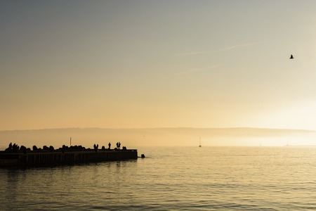 silhouette of unknown people on a pierの写真素材