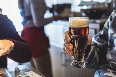 Man holding a brown beer in a vintage pub
