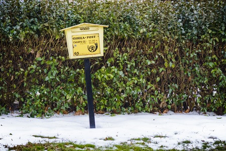 Bulgarian mailbox in the snow against a green hedge
