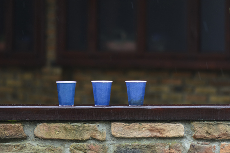 tree paper cups on a bar, under the rain against blurry backgroundの写真素材