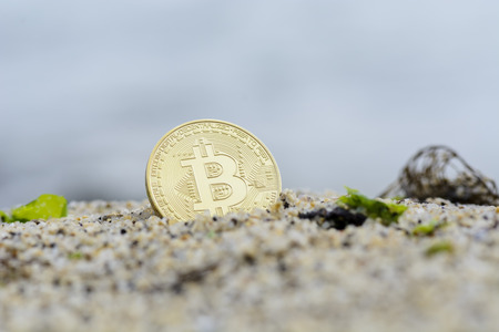 Close up of a Bitcoin coin on the beachの写真素材