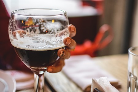 girl holding a glass half filled with dark beerの写真素材