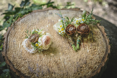 weeding boutonnieres with rose and pine cone on a wooden stump.の写真素材