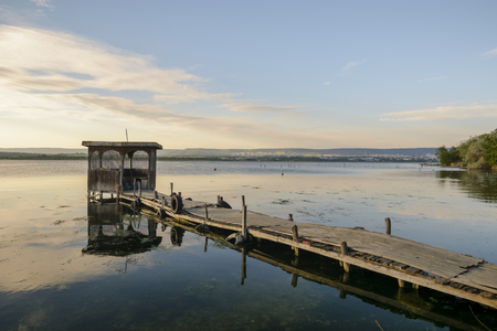 Wooden pier on a lake with a fishing hut. sunset with calm waterの写真素材