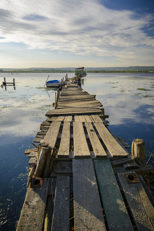 Wooden pier on a lake with a fishing hut. sunset with calm waterの写真素材