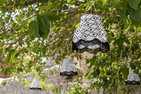 White lamp suspended to a branch, with fringe against blurry back ground.の写真素材