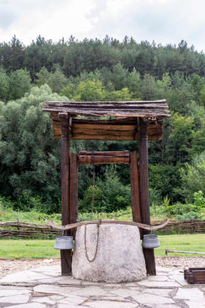 Wooden hand made well in a garden against a forest.の写真素材