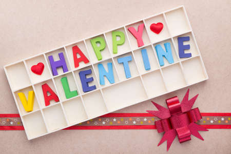 Wooden box of Happy Valentine's wooden alphabets on top of ilight wood background with colored ribbon and bowの写真素材