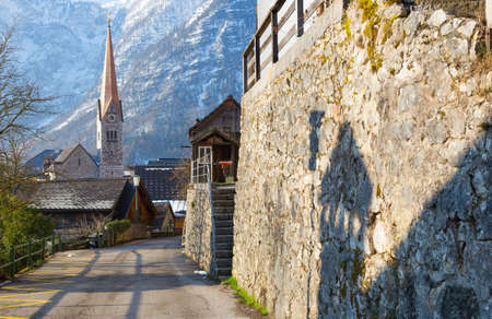 Clock Tower of Hallstatt seen from a road in morning light with mountain in backgroundの写真素材
