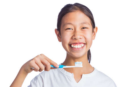 Happy asian girl holding toothbrush, looking and smiling at camera, isolated white background