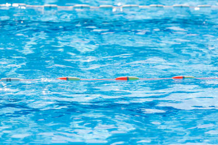 Close up of swimming pool lane divider line on a bright sunny day, selective focus on the color...