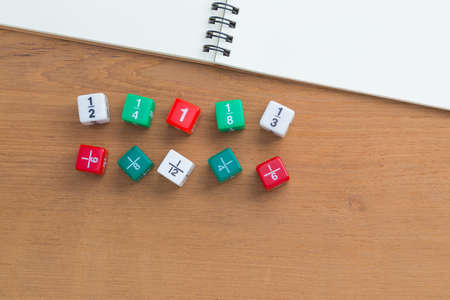 Color fraction dices, blank white notebook on wooden desk, with copyspace for text