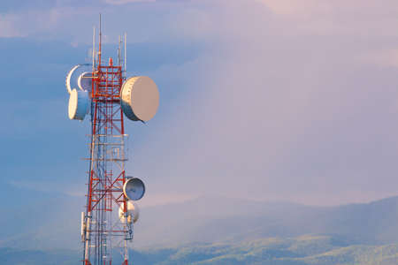 Telecommunication tower at sunset with warm sunlight and blue cloudy sky after the rain, mountain...
